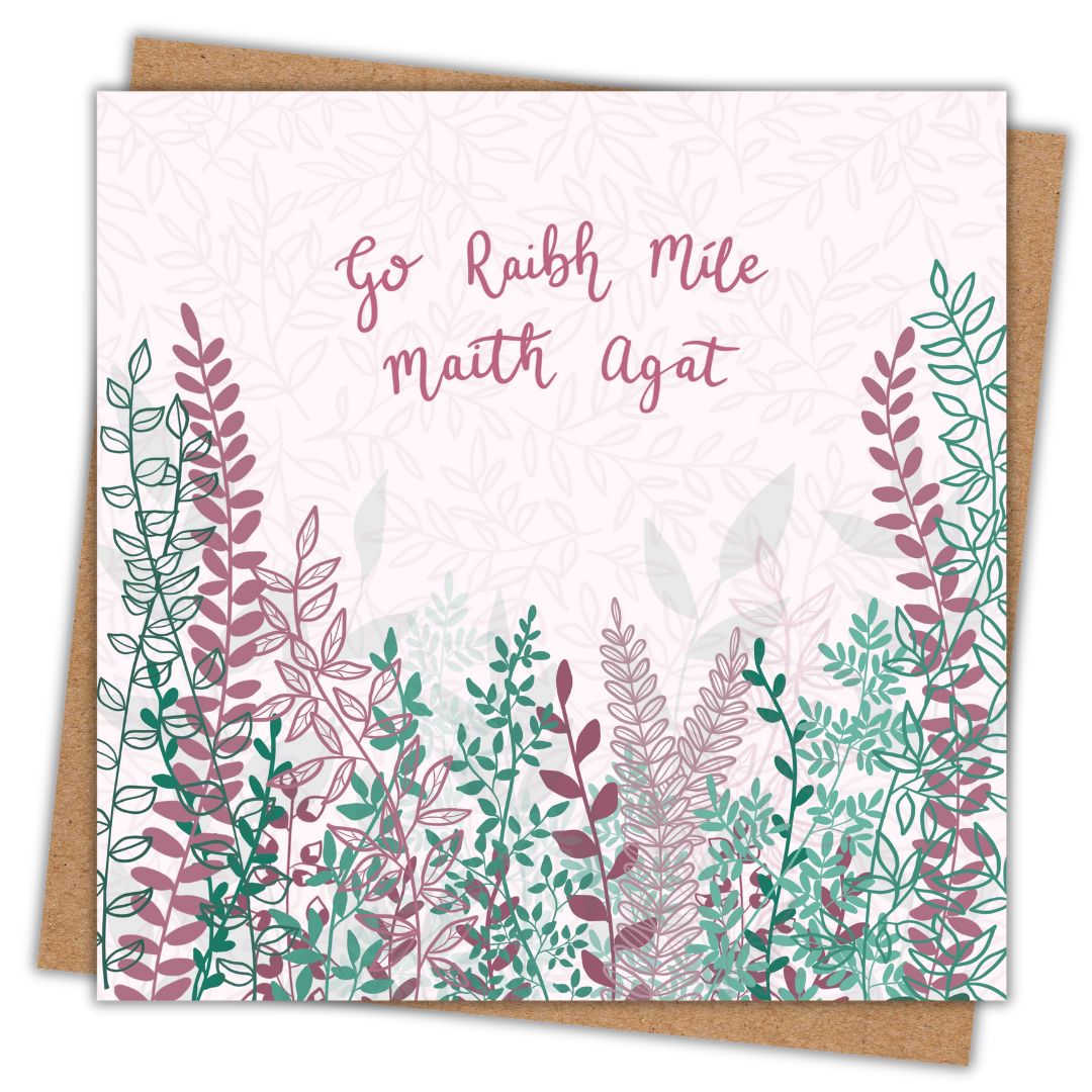 Irish botanical thank you card with the words Go Raibh Míle Maith Agat hand written across the upper half of the card in a dark pink hand writing. Beneath the writing are lots of pink and green toned leaves and branches. Under the card is a recycled brown Kraft envelope.