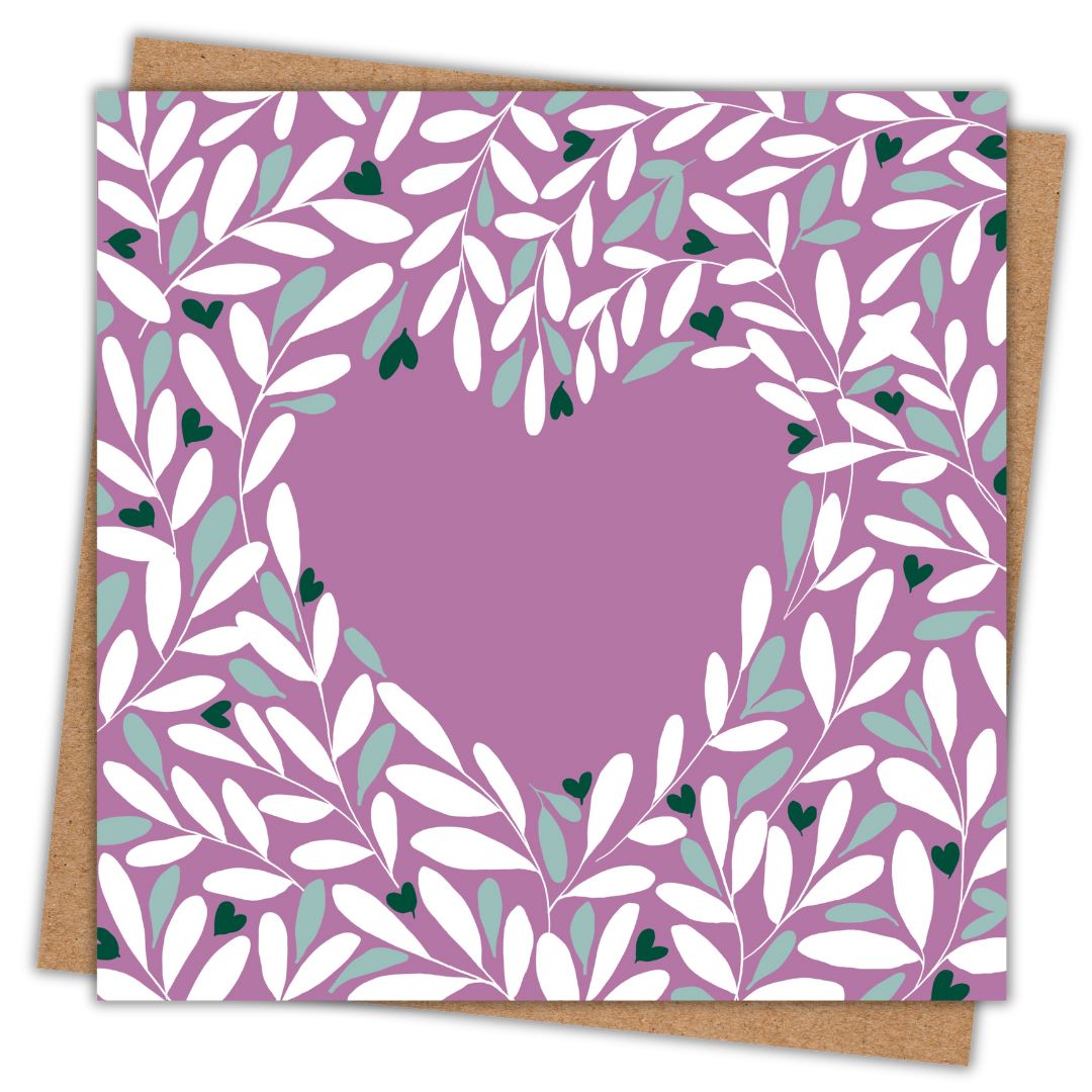 Simple image of a square greeting card with its Kraft brown envelope behind it. The card design has a muted purple-mauve background, featuring a heart-shaped cutout surrounded by an intricate leafy pattern in white, light green, and dark green accents. The delicate botanical design creates a soft and elegant feel.