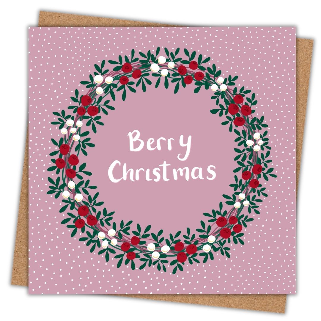 Irish Christmas card which says Berry Christmas in white in the centre of a green, red, and white wreath. The background of the card is pink.