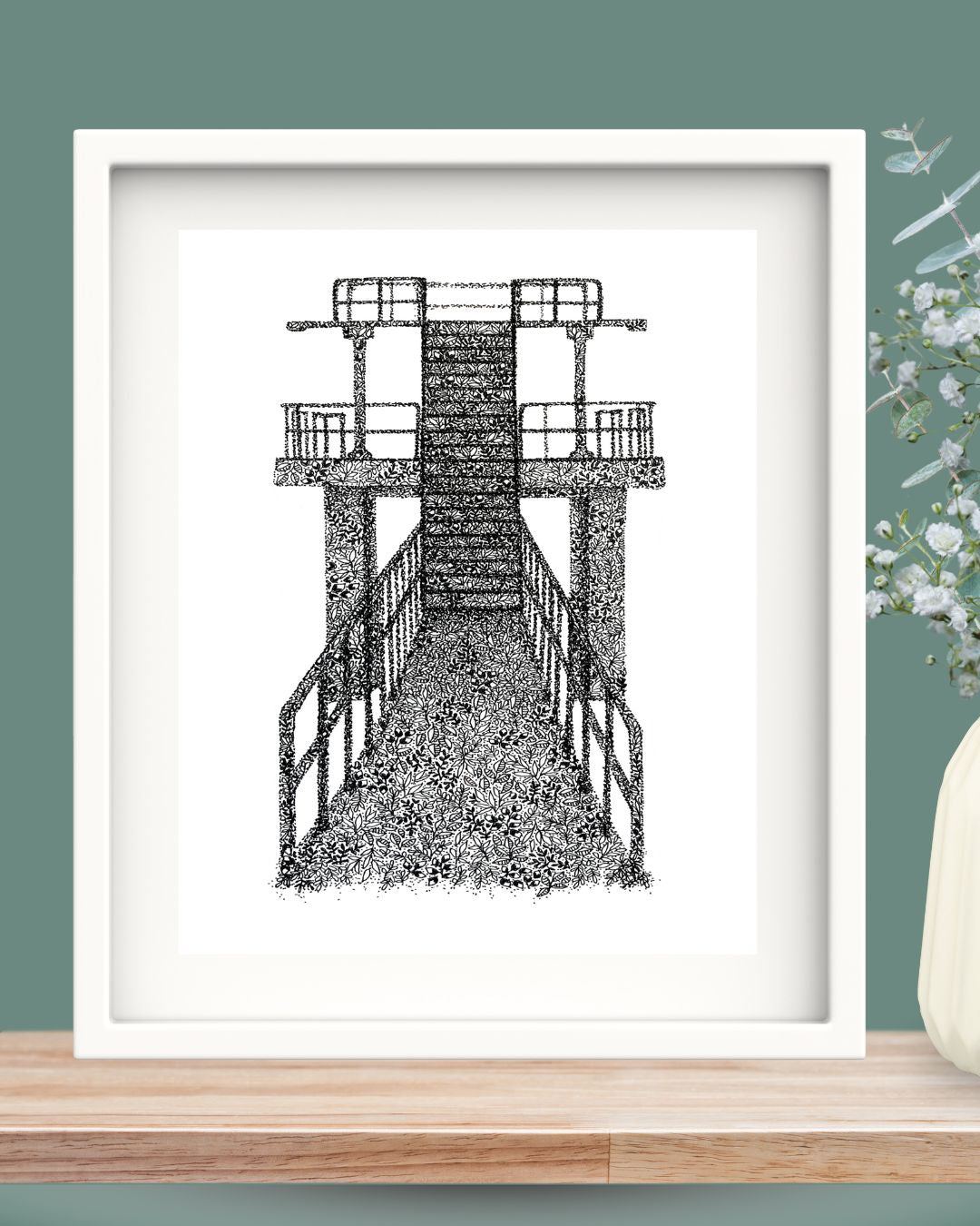 Blackrock Diving Board Salthill Galway is illustrated here in black fineliner pen. The art print is created out of leaf shapes and dots in Una Heaney's interpretation of the West of Ireland landmark. It's framed in a white solid wood frame.