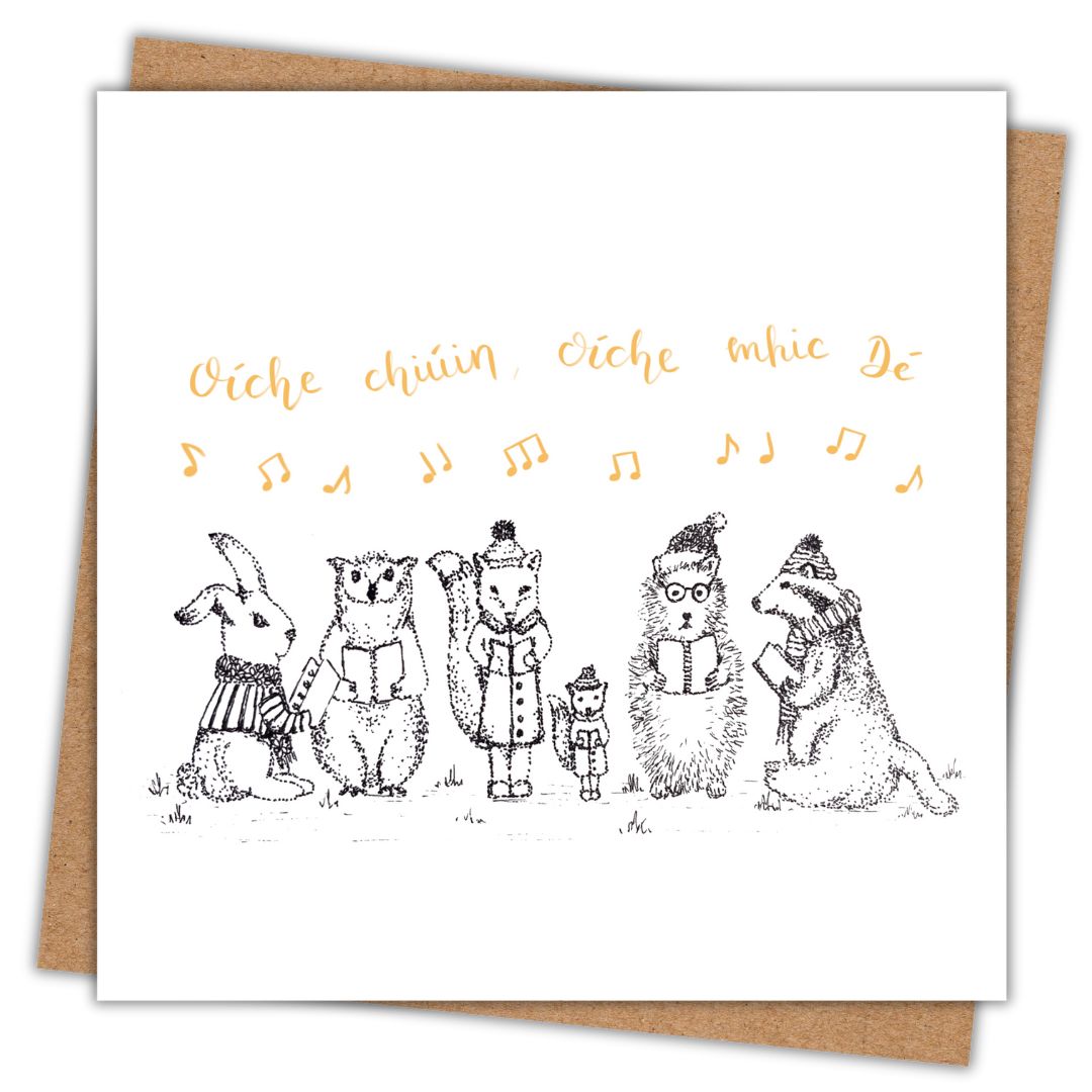 A square white greeting card with a black line-art illustration of five animals singing together, with gold handwritten text above and gold musical notes across the top. A brown kraft envelope is partially visible behind the card.