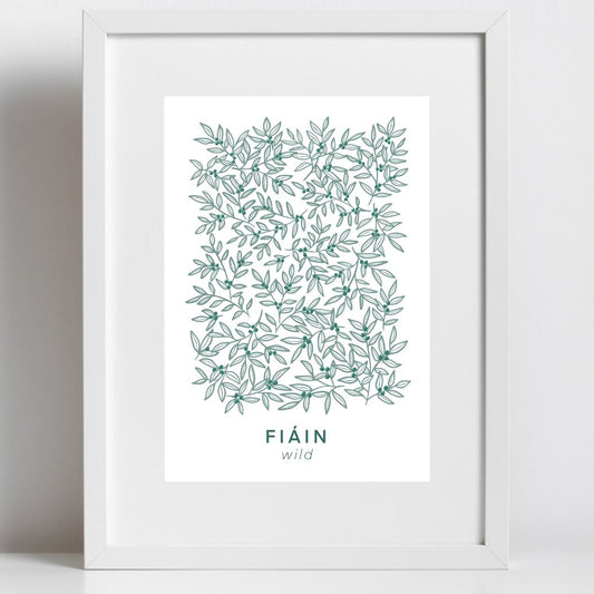 A framed botanical art print featuring an intricate, hand-drawn pattern of intertwining green leaves and small berries. Below the design, the Irish word 'FIÁIN' is displayed in deep green uppercase letters, with the translation 'wild' written in a delicate, lowercase font beneath it. The artwork is set in a simple white frame and white mount.