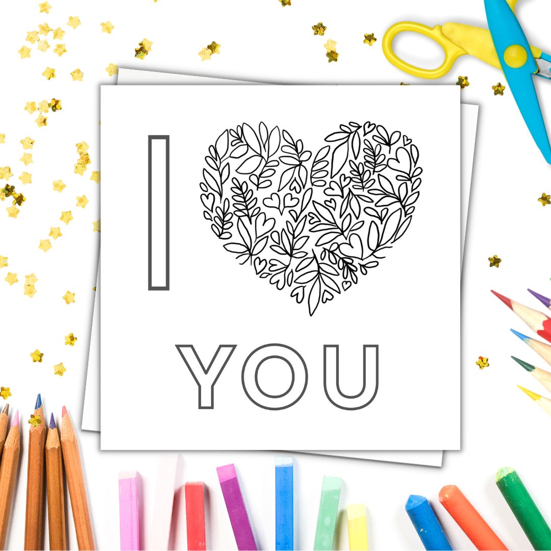 Image shows colour in card with the phrase I LOVE YOU . LOVE is a heart made from floral drawings and tiny hearts. Image laid on a white surface with colourful crayons pencils and gold stars.