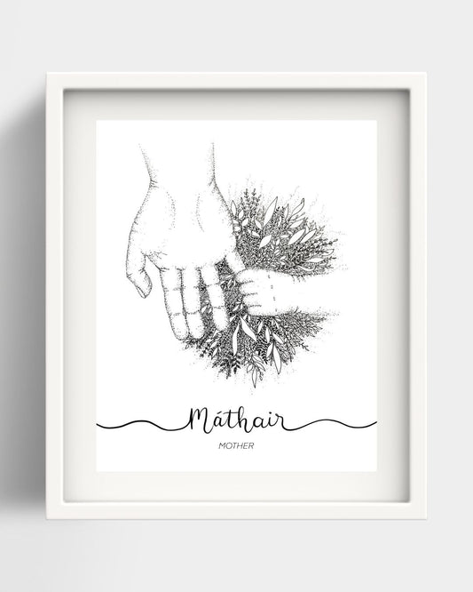 A framed art print of an adult hand holding a child's hand. Where the hands meet there is a big burst of foliage. Underneath the drawing the Irish word "Máthair" is handwritten in black script. Beneath that is the translation Mother. The background is white, the frame and the mount are also both white.