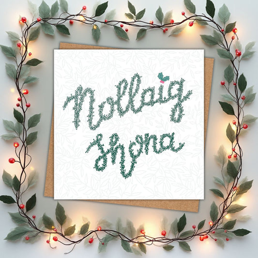 Irish Christmas card with the words Nollaig Shona written in a continuous vine of leaves and buds in a deep green. There is a sprig of holly above the i in Nollaig.