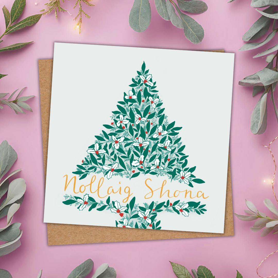 Christmas card with a Christmas tree made of green leaves, white holly and red berries. Towards the base of the tree are the words Nollaig Shona (Irish for Happy Christmas) in gold writing.