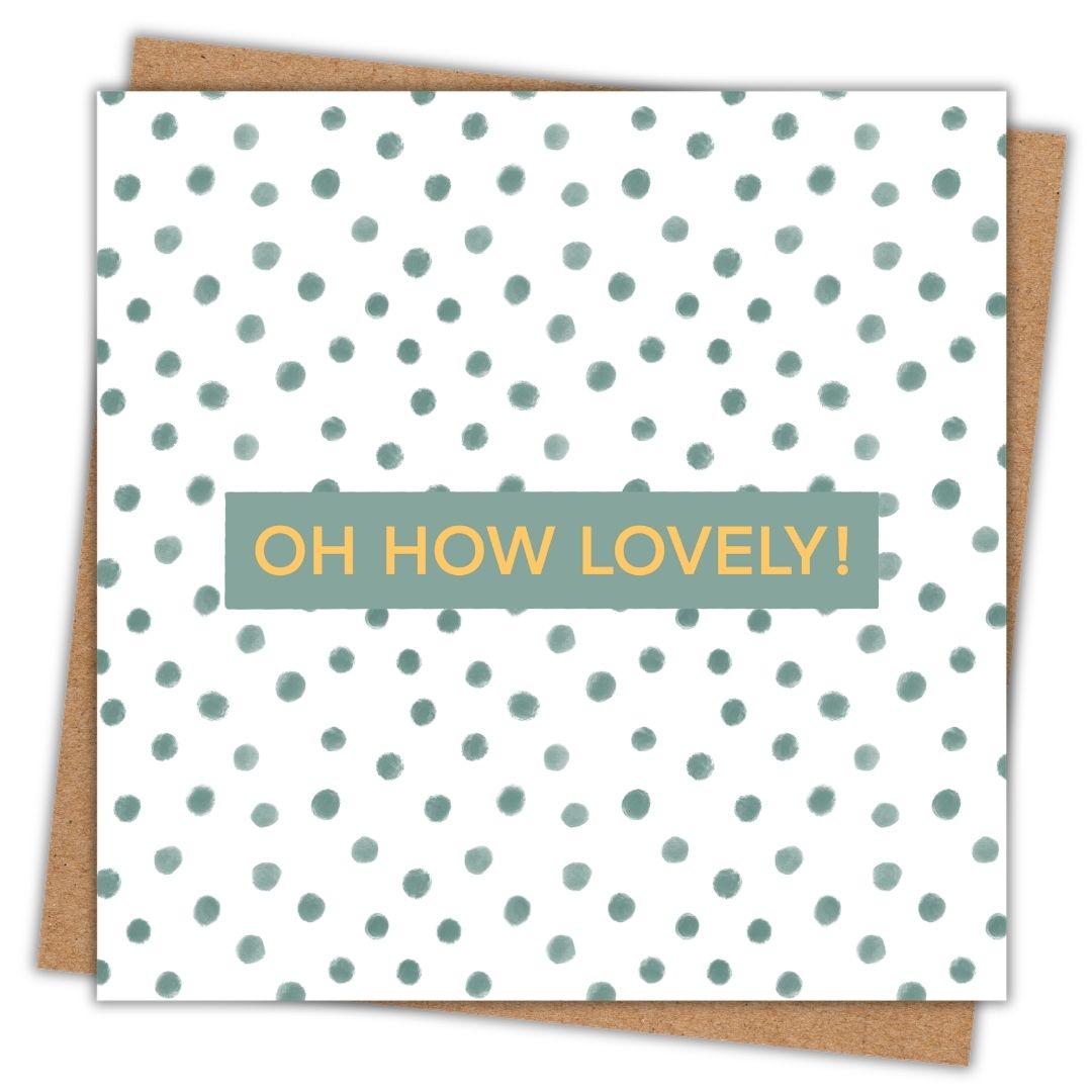 A celebration card with the words "Oh How Lovely!" in a gold font in the centre. The words are set on a small dark green background and the rest of the card is made up of dark green soft natural looking polka dots. It's a very pretty celebration card with a neutral tone to it. There's a kraft brown envelope under the card.