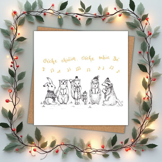 Cute Christmas card of woodland animals carol singing in Irish. Above the animals in gold writing it says "Oíche chiúin, oíche mhic Dé" which is Silent Night, Holy Night, in Irish.