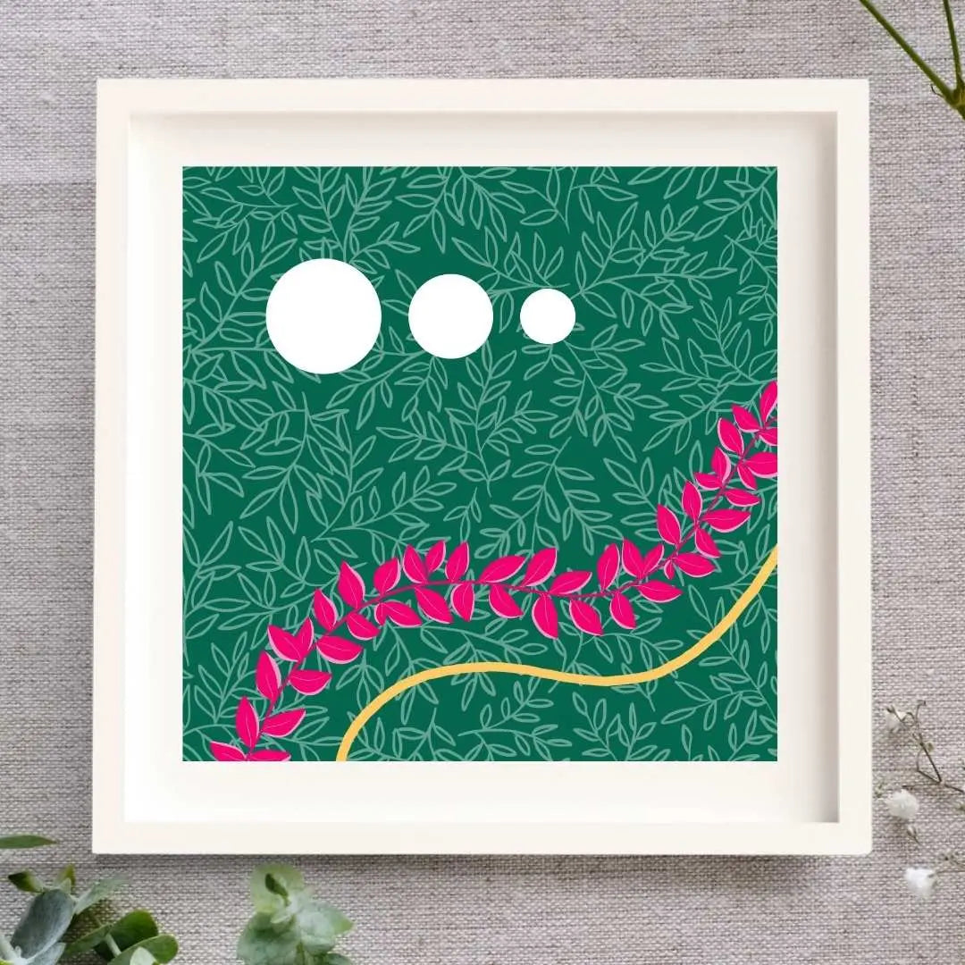 Framed artwork of a leafy illustration. There's a dark green background with a layer of light green leaf outlines on top. There are three white circles in the top half, to the left ranging from big to small, left to right. In the bottom half there is a wave of bright pink leaves passing though the print, and below that following the same curve is a wave of gold created by gold leaf. The print is in a white mount, white wooden frame set on a natural cloth background with foliage around it.