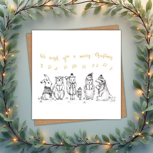 Simple Christmas card with a group of carol singing woodland animals. Above them there are musical notes in gold, and the phrase "We wish you a merry Christmas"