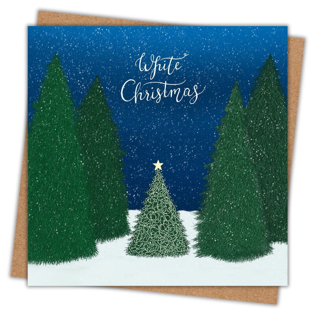 A square Christmas greeting card with a winter forest illustration, featuring dark green pine trees, a smaller decorated tree, snow, and the words 'White Christmas' in white script. The card is shown slightly offset over a brown envelope on a white background.