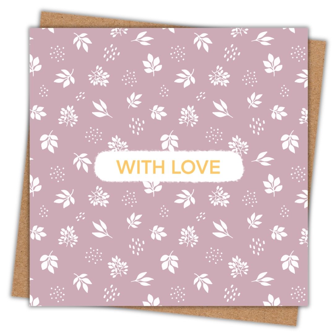 Botanical themed greeting card with the words "With Love" in the centre. The words are written in a simple gold font with a small white surround. The rest of the card is a botanical pattern of white leaves and petals set on a dusty dusk pink. The card is lying on a kraft brown envelope.